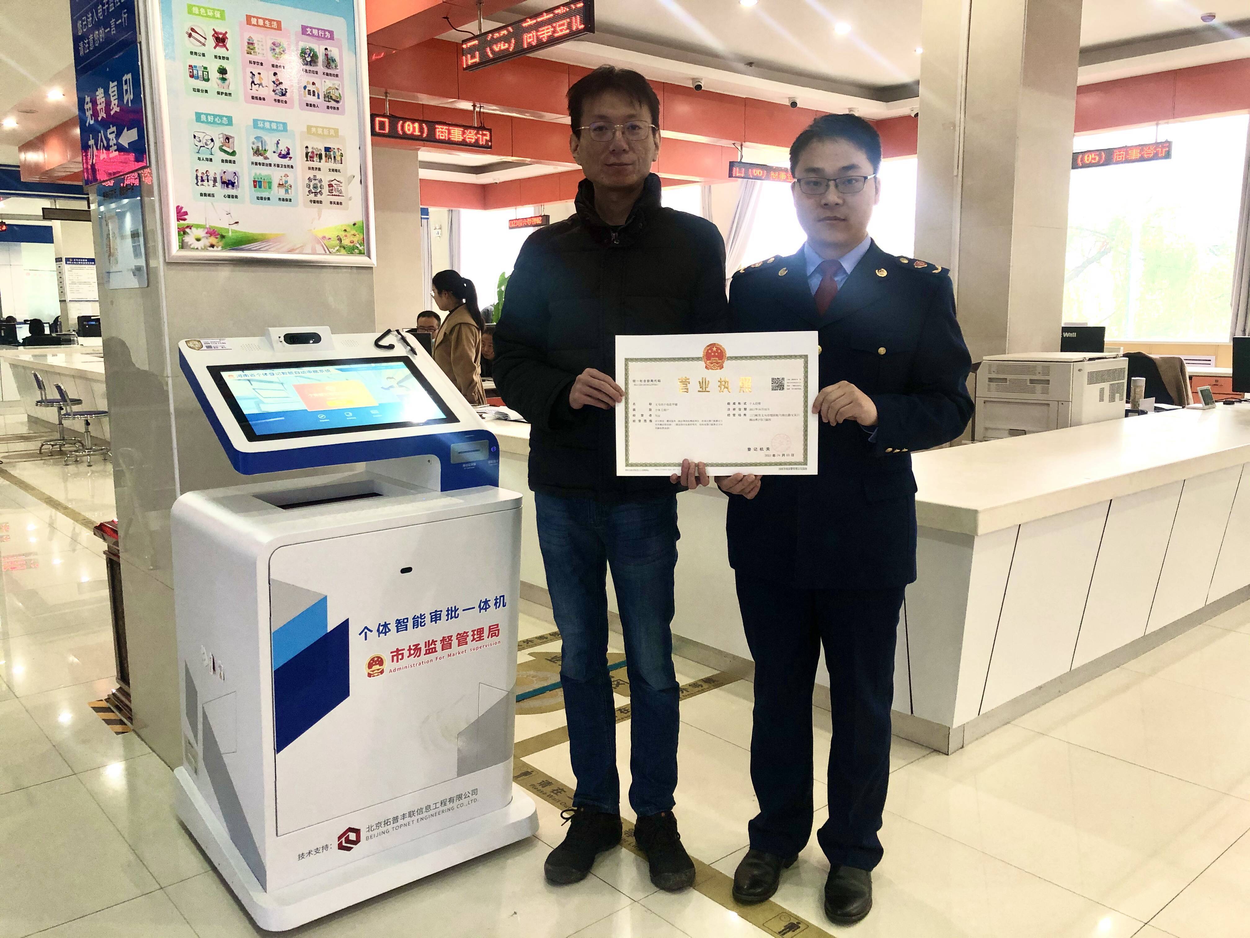 义马市个体工商户马宝(左一)顺利拿到个体工商户营业执照 李艳玲 摄