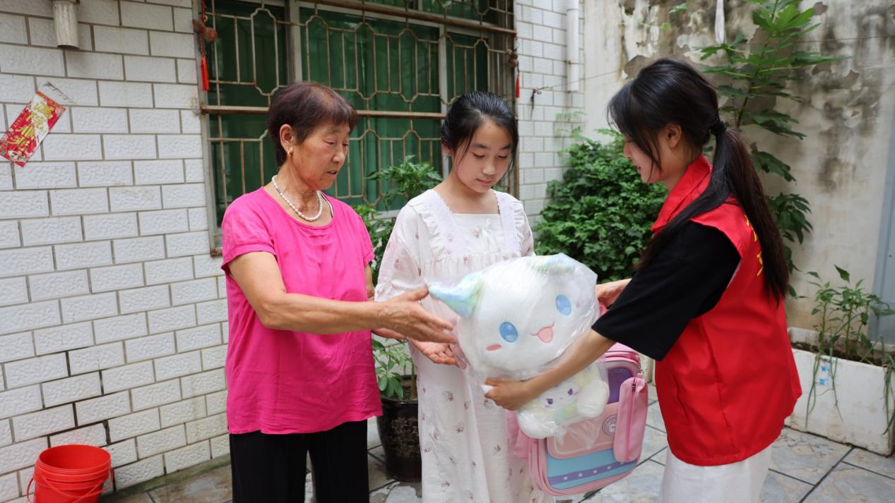  周诗雨（右一）把书包文具送到刘一诺手中 孙世杰 摄